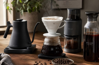 Coffee gear flat lay with electric gooseneck kettle, burr grinder, V60 dripper, and cold brew pot on walnut counter
