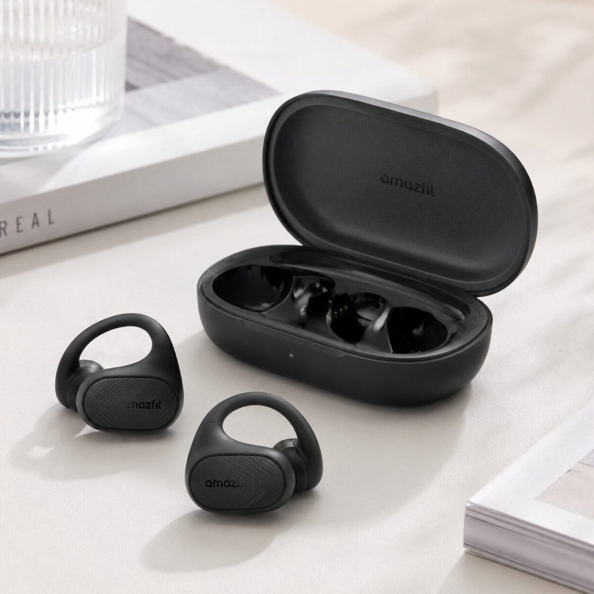 Amazfit Up open ear clip earbuds in black next to charging case on desk