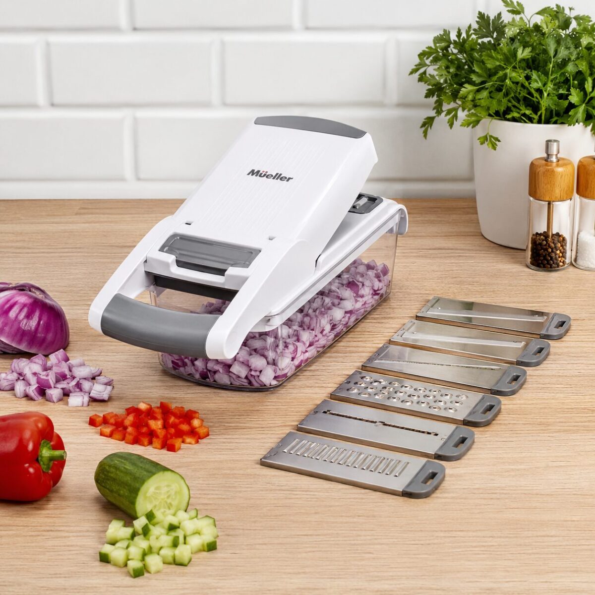Mueller Vegetable Chopper white and grey with clear container and blades on a kitchen counter
